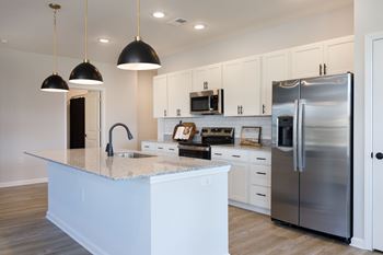 A modern kitchen with a granite countertop and stainless steel appliances.